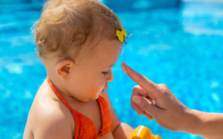 Mother smears sunscreen on the child face. Selective focus. Kid.の写真素材
