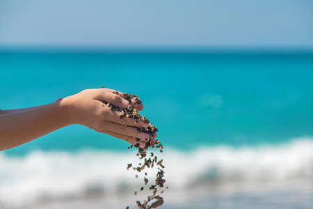 Stones in the hands of a child at sea. Selective focus. Kid.の写真素材