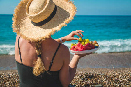 A woman at the sea eats fruit. Selective focus. Nature.の写真素材