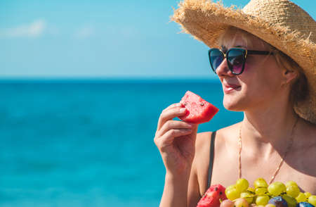 A woman at the sea eats fruit. Selective focus. Nature.の写真素材