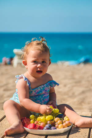 The child eats fruit by the sea. Selective focus. Kid.の写真素材