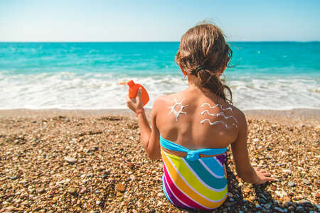 The child smears sunscreen on her back. Selective focus. Kid.の写真素材