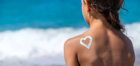 The child smears sunscreen on her back. Selective focus. Kid.の写真素材