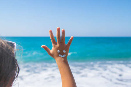 The child smears sunscreen on her hand. Selective focus. Kid.の写真素材
