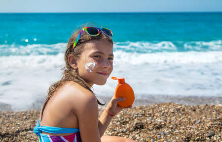 The child is putting sunscreen on her face. Selective focus. Kid.の写真素材