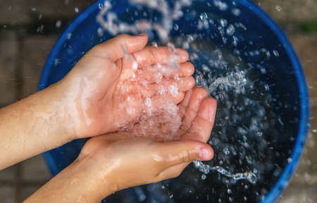 The water flows into the hands of the child. Selective focus. Kid.の写真素材