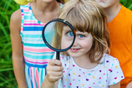 Children look at a magnifying glass on the nature. Selective focus. Nature.