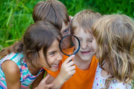 Children look at a magnifying glass on the nature. Selective focus. Nature.