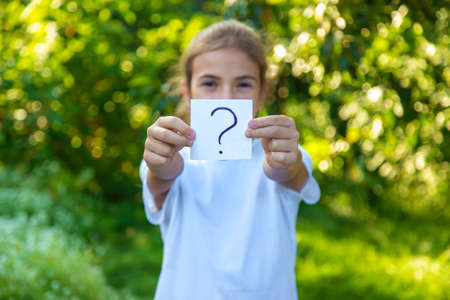 The child holds a paper with a question mark. Selective focus. Kid.の写真素材