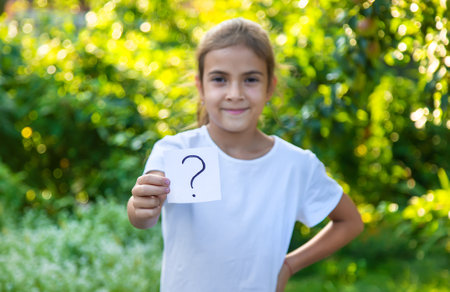 The child holds a paper with a question mark. Selective focus. Kid.の写真素材