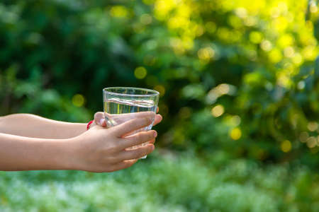 The child drinks water from a glass. Selective focus. Kid.