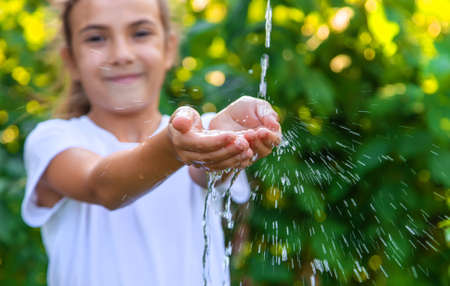 The water flows into the hands of the child. Selective focus. Nature.の写真素材