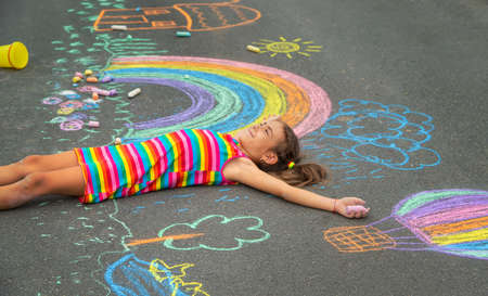 The child draws with chalk on the asphalt. Selective focus. Kid.