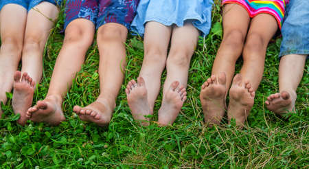 Children's feet lie on the grass. Selective focus. Kid.の写真素材