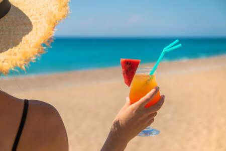 A woman holds a cocktail in her hand against the background of the sea. Selective focus. Nature.の写真素材