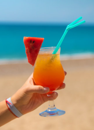A woman holds a cocktail in her hand against the background of the sea. Selective focus. Nature.の写真素材