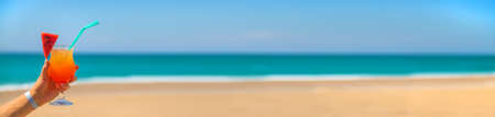 A woman holds a cocktail in her hand against the background of the sea. Selective focus. Nature.の写真素材