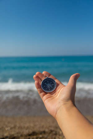 Compass in hands against the background of the sea. Selective focus. Travel.の写真素材