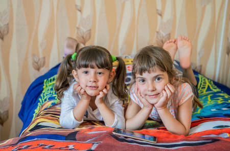 The child is playing the phone on the bed. Selective focus. Kid.の写真素材