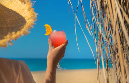 Woman on the beach holding a cocktail in her hands. Selective focus. Drink.の写真素材