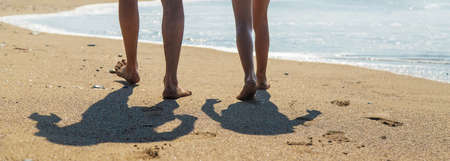 Legs of people walking along the beach. Selective focus. Sea.