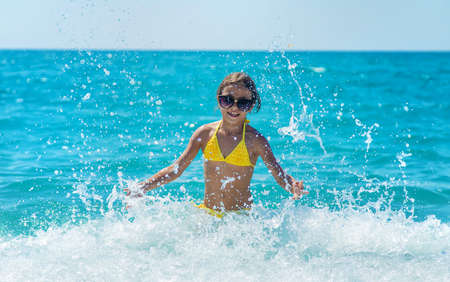 A child splashes water on the sea. Selective focus. People.の写真素材