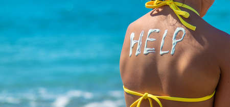 The child puts sunscreen on her back. Selective focus. Kid.