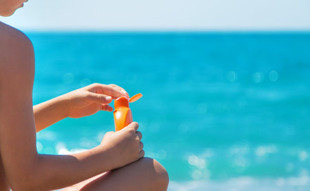 Sunscreen in hands on the beach. Selective focus. Sea.の写真素材
