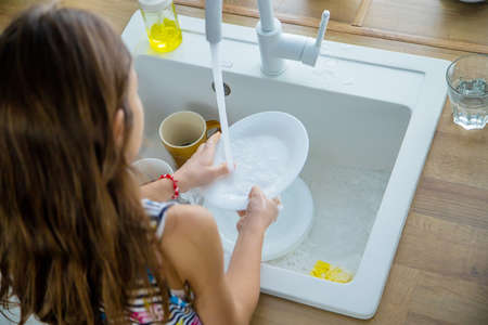 Children wash dishes in the kitchen. Selective focus. Kid.の写真素材