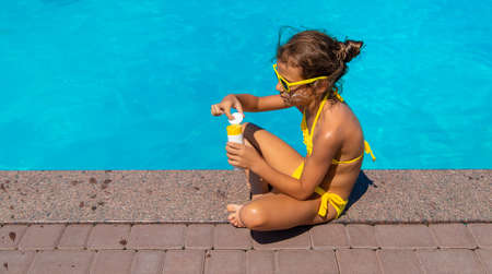 Sunscreen near the pool on the face of the child. Selective focus.