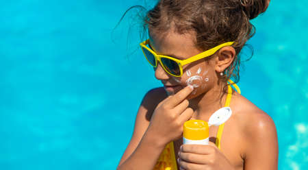 Sunscreen near the pool on the face of the child. Selective focus.
