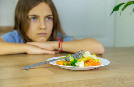 The child eats vegetables on a chair. Selective focus.の写真素材