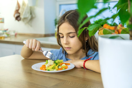 The child eats vegetables on a chair. Selective focus.の写真素材