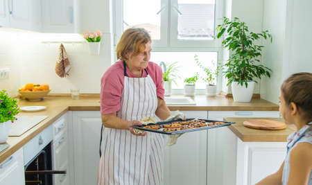 Grandmother old woman in the kitchen bakes prepares the dough in the kitchen. selective focus. food.