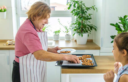 Grandmother and granddaughter are baking cookies in the kitchen. selective focus. food.の写真素材