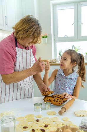 Grandmother and granddaughter are baking cookies in the kitchen. selective focus. food.の写真素材