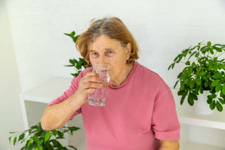 The old woman drinks water. selective focus. people.の写真素材