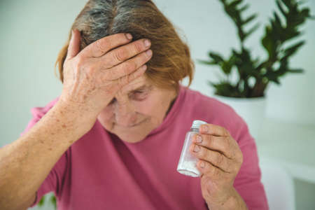 An old woman drinks a pill for a headache. selective focus. people.