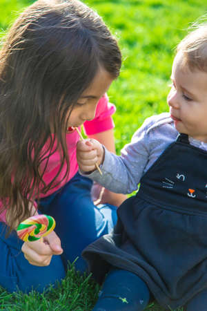 A child eats a lollipop in the park. selective focus. kd.