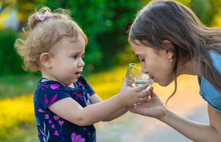 The child drinks water from a glass. Selective focus.