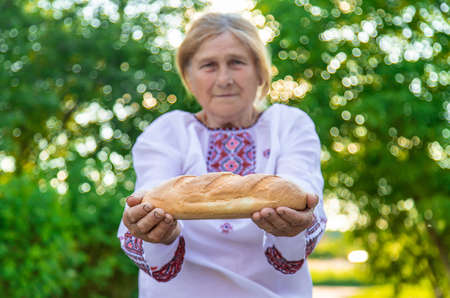 Grandmother with Ukrainian bread in her hands. Selective focus.の写真素材