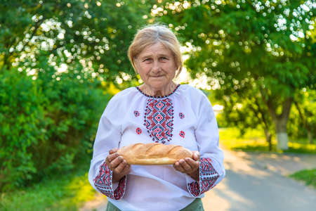 Grandmother with Ukrainian bread in her hands. Selective focus.の写真素材