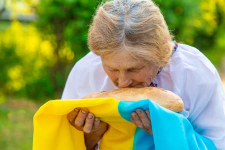 Grandmother with Ukrainian bread in her hands. Selective focus.の写真素材