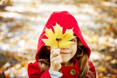 child in a red coat with autumn leaves. Love autumn. Selective focus.の写真素材