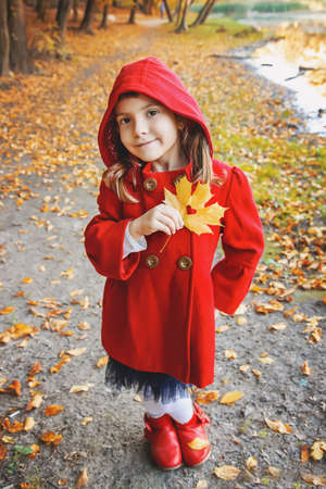 child in a red coat with autumn leaves. Love autumn. Selective focus.の写真素材