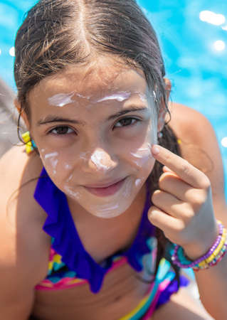 Child near the pool smears sunscreen. Selection focus.