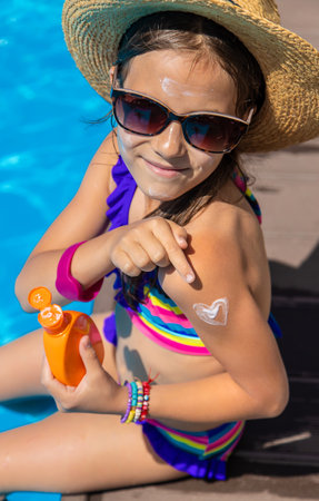 Child near the pool smears sunscreen. Selection focus.