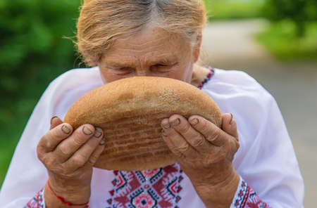 Grandmother with Ukrainian bread in her hands. Selective focus.の写真素材