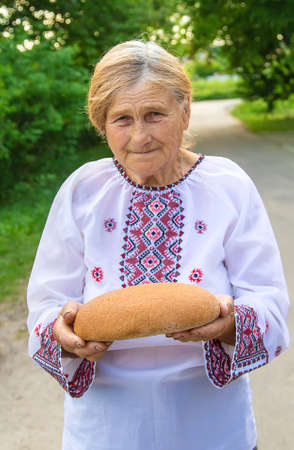 Grandmother with Ukrainian bread in her hands. Selective focus.の写真素材