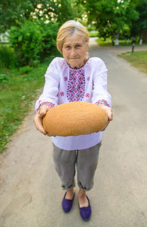 Grandmother with Ukrainian bread in her hands. Selective focus.の写真素材